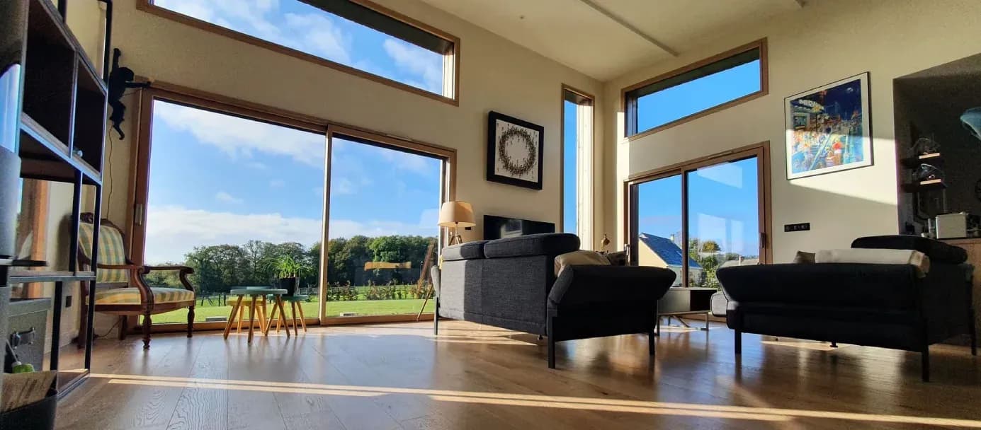 Intérieur moderne avec baies vitrées donnant sur la campagne normande